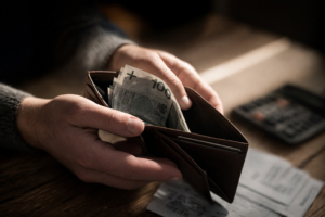 Portfel z niewielką ilością pieniędzy i rachunkami na stole, symbolizujący realną wartość minimalnej krajowej na rękę w 2026 roku